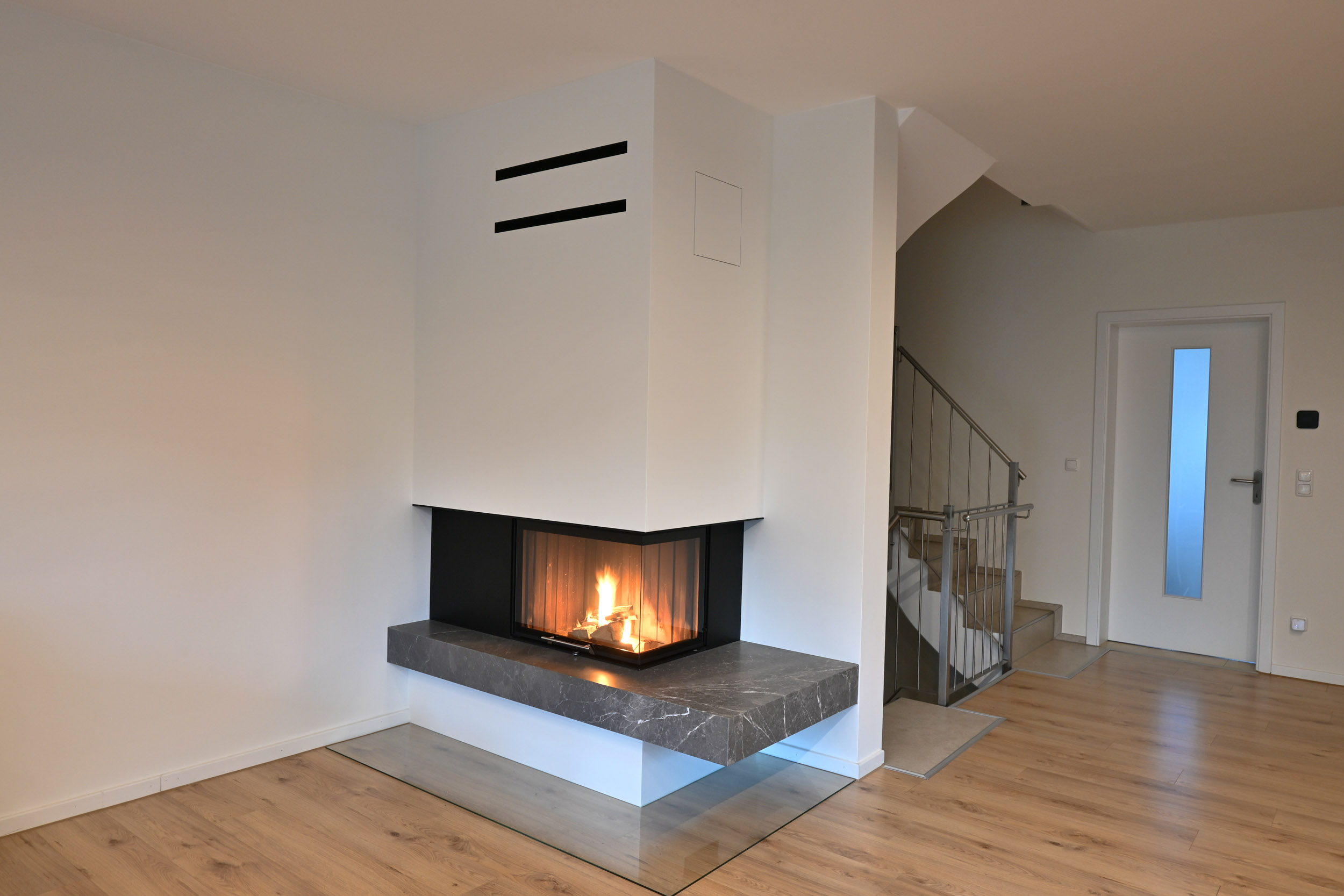 weißer brennender Eckkamin in einem leeren Raum mit Holzfußboden